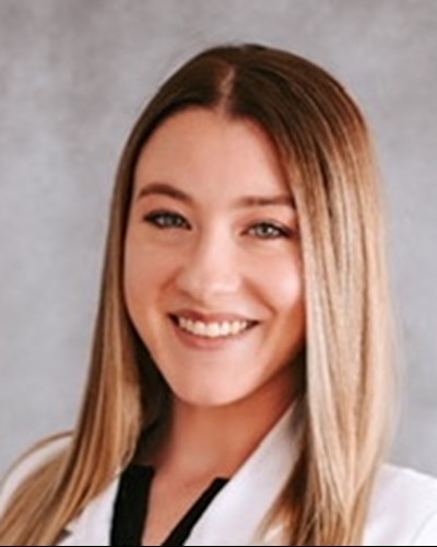 Hannah is shown posing in her white WVU School of Pharmacy white coat.